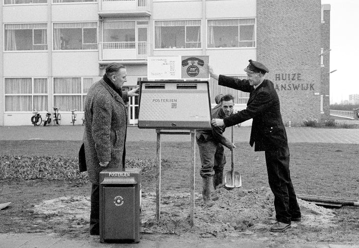 Historische foto van een postbode bij een postbus