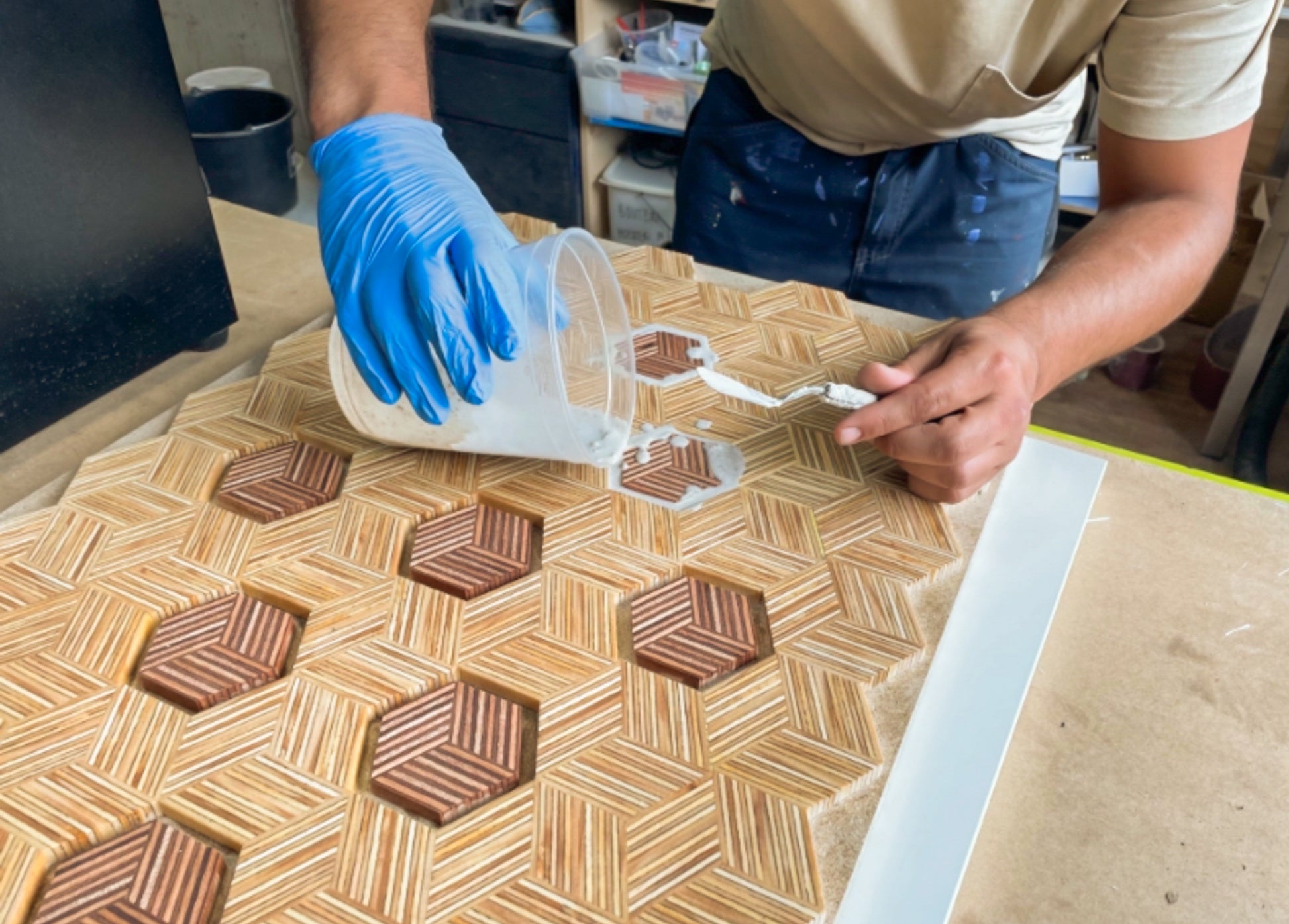 een man giet lijm op de tafel om de Koffietafel met steen van de Domtoren te maken